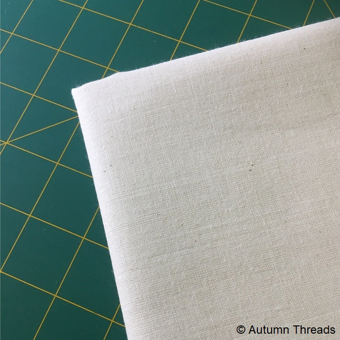 Folded calico fabric on a cutting mat.
