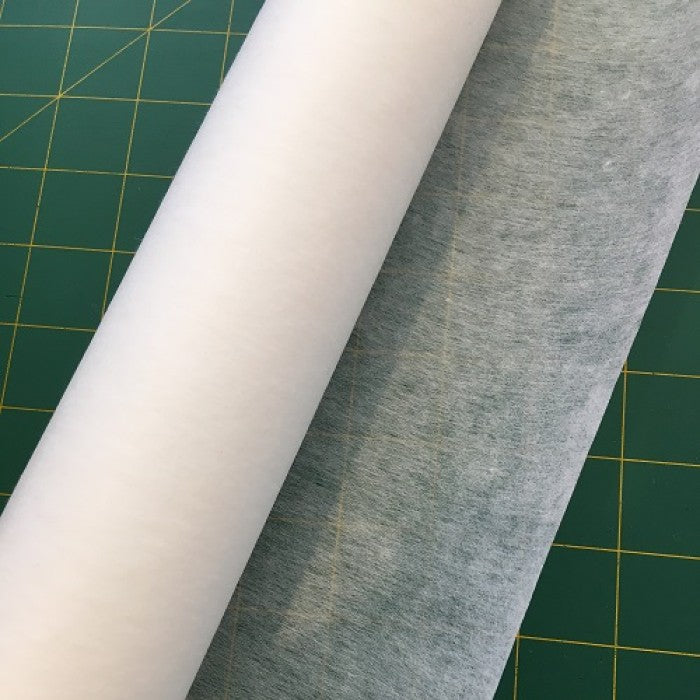 Roll of thin white interfacing on a cutting board.