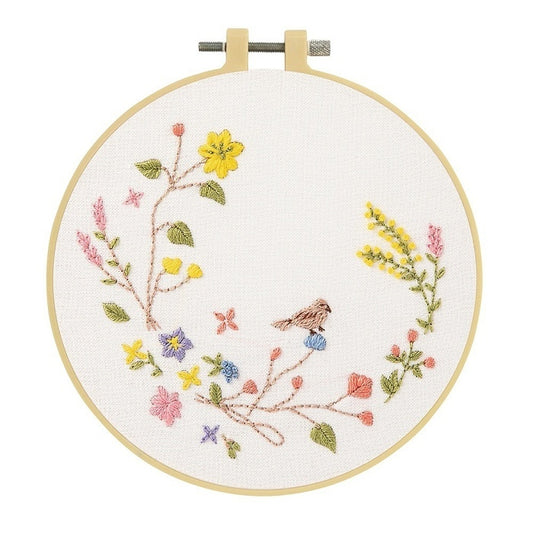 Embroidery hoop with a small bird on a floral branch in pastel colours.