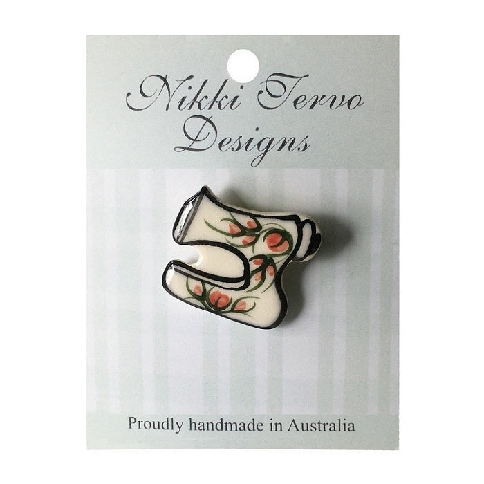Cream ceramic sewing machine brooch with red flowers.