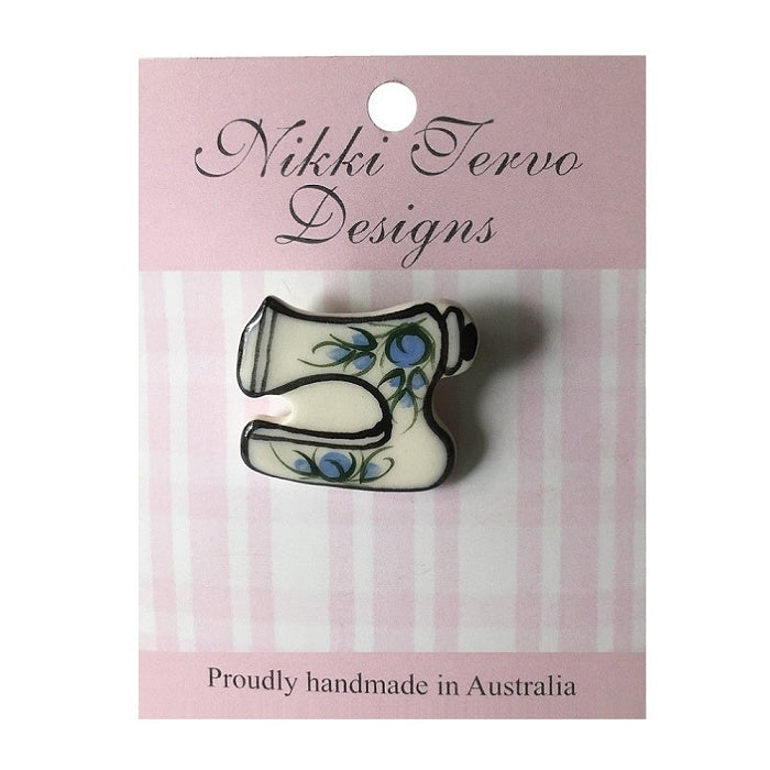 Cream ceramic sewing machine brooch with blue flowers.