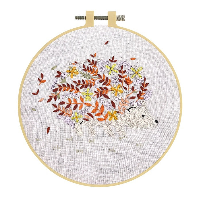 Embroidery hoop with an autumn coloured floral hedgehog and beige background.