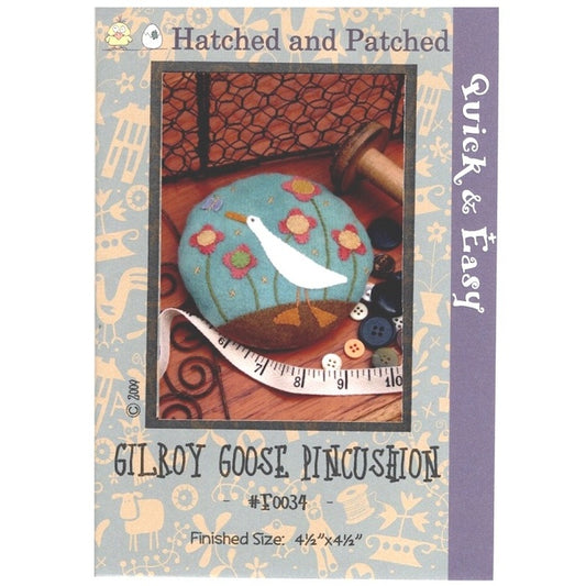 Pattern cover of pincushion with appliqued white goose and flower garden.