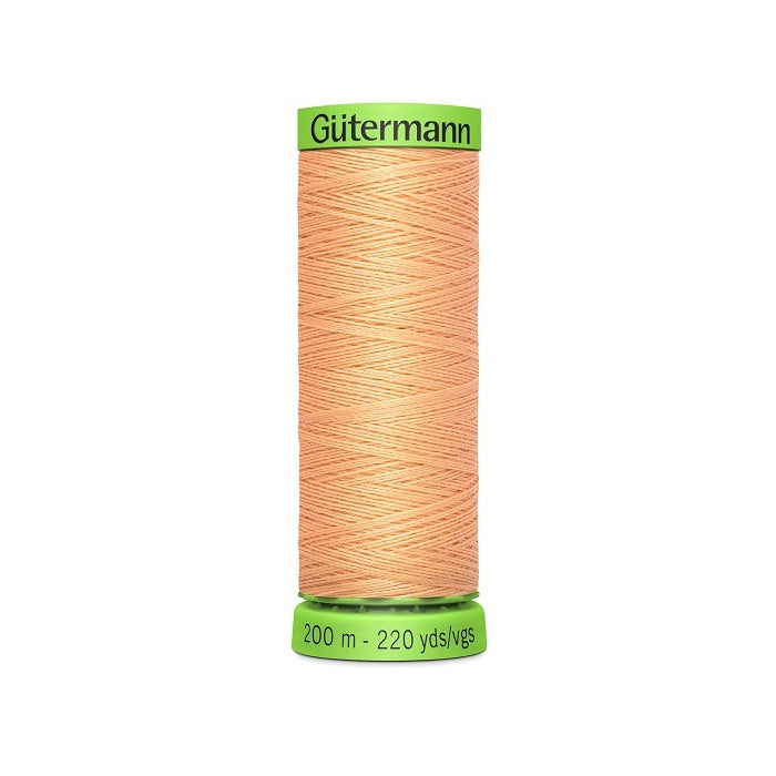 Spool of apricot beige extra fine thread with Gutermann branding.