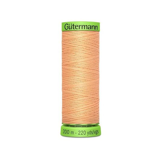 Spool of apricot beige extra fine thread with Gutermann branding.