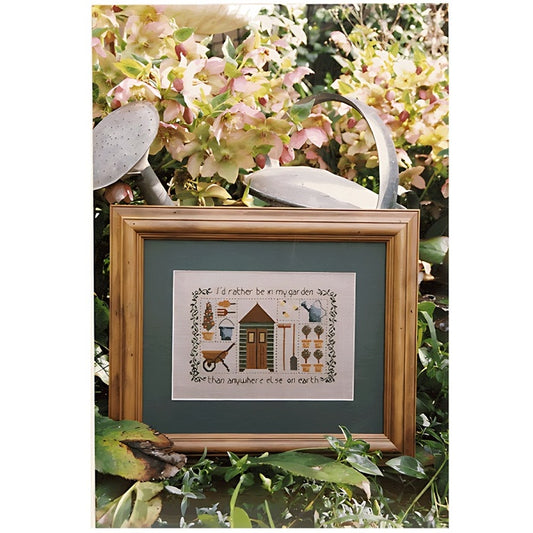 Framed cross stitch of garden potting shed and tools.
