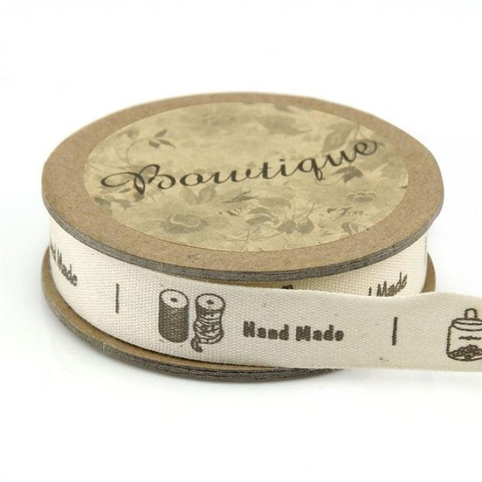 Spool of ribbon with sewing notions and the words Hand Made.