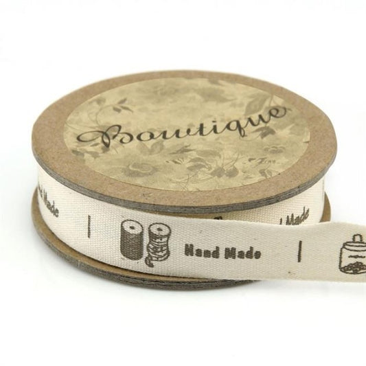 Spool of ribbon with sewing notions and the words Hand Made.