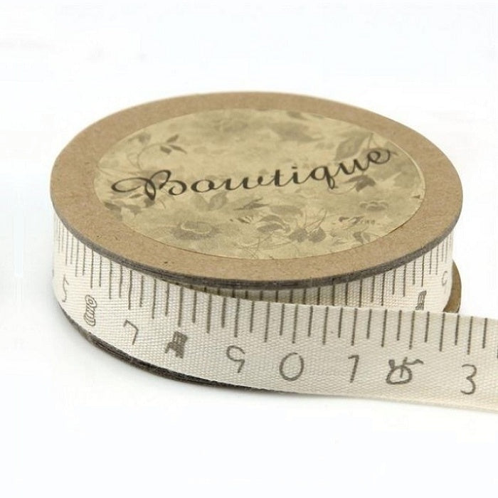 Spool of ribbon with tape measure increments.