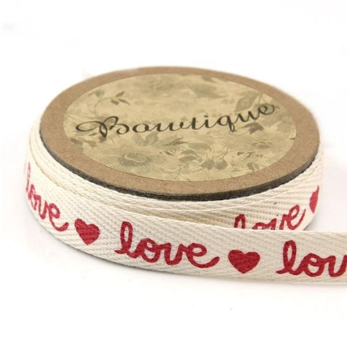 Spool of cream ribbon with hearts and the word love written in red.