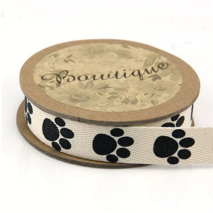 Spool of cream cotton ribbon with black paw prints.