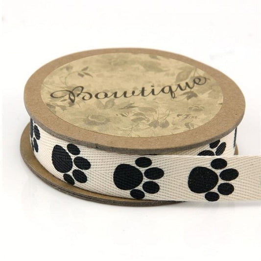 Spool of cream cotton ribbon with black paw prints.