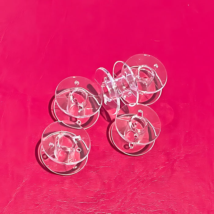 Five transparent sewing machine bobbins without packaging.