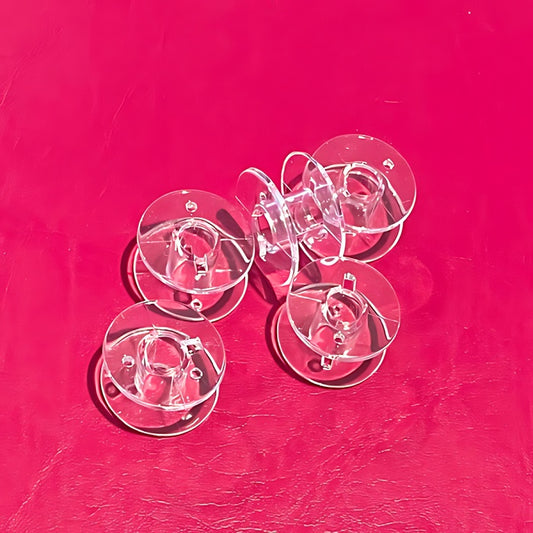 Five transparent sewing machine bobbins without packaging.