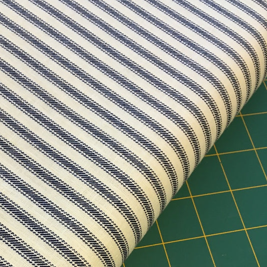 Roll of navy and cream striped fabric on a cutting mat.